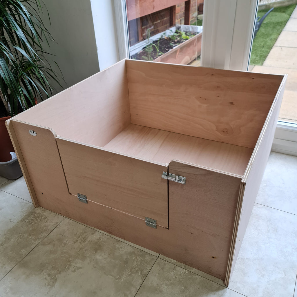A wooden whelping box for dogs with a large lockable entrance, designed for the maternity and whelping needs of pregnant dogs.